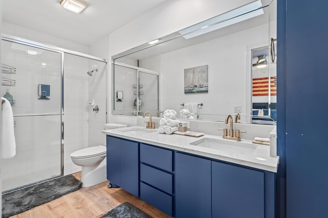 full bath featuring double vanity, a stall shower, a sink, and wood finished floors