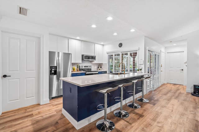 kitchen with visible vents, appliances with stainless steel finishes, light countertops, white cabinetry, and a sink