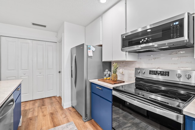 kitchen featuring visible vents, white cabinets, appliances with stainless steel finishes, light countertops, and blue cabinetry