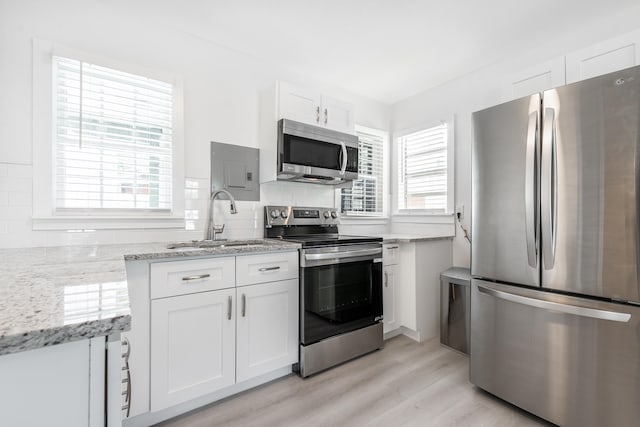 kitchen with white cabinetry, stainless steel appliances, a healthy amount of sunlight, and light hardwood / wood-style flooring