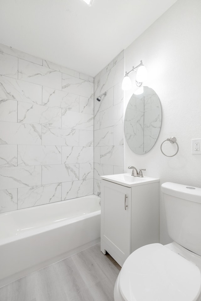 full bathroom featuring vanity, tiled shower / bath combo, toilet, and hardwood / wood-style floors