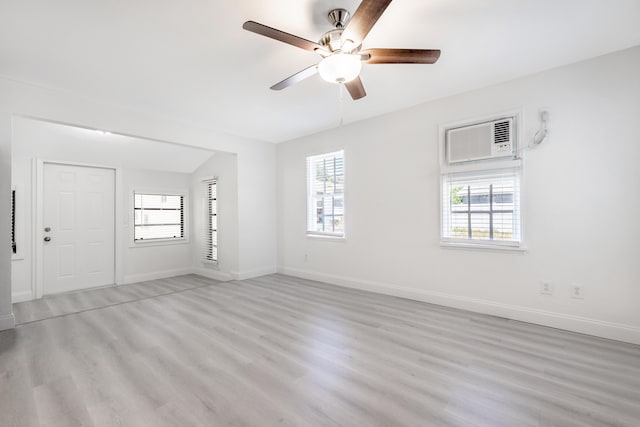 unfurnished living room with a wall mounted AC, vaulted ceiling, ceiling fan, and light wood-type flooring