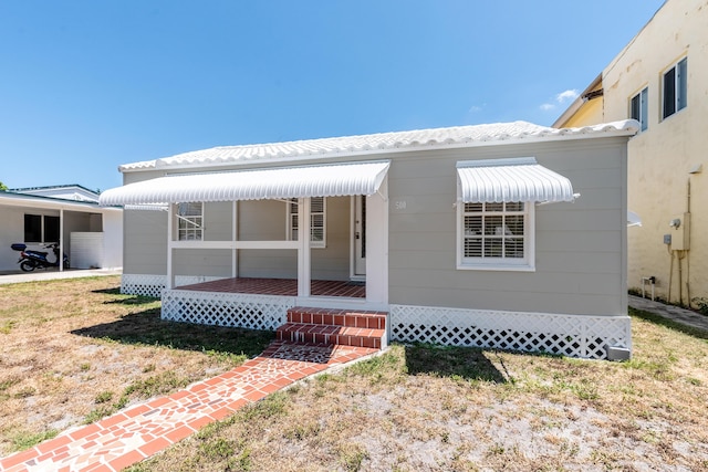 back of property with a porch and a lawn