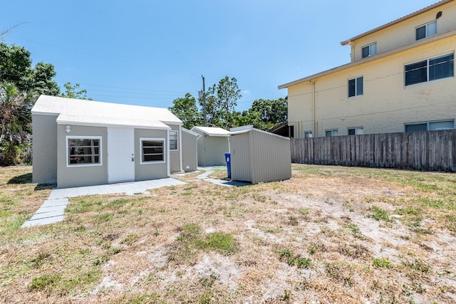 back of property with a shed and a yard