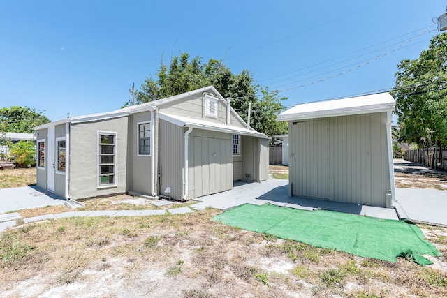 back of house with a storage unit