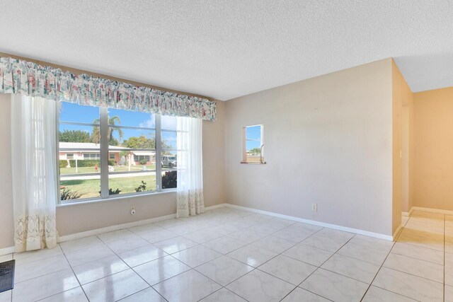 tiled empty room with a textured ceiling