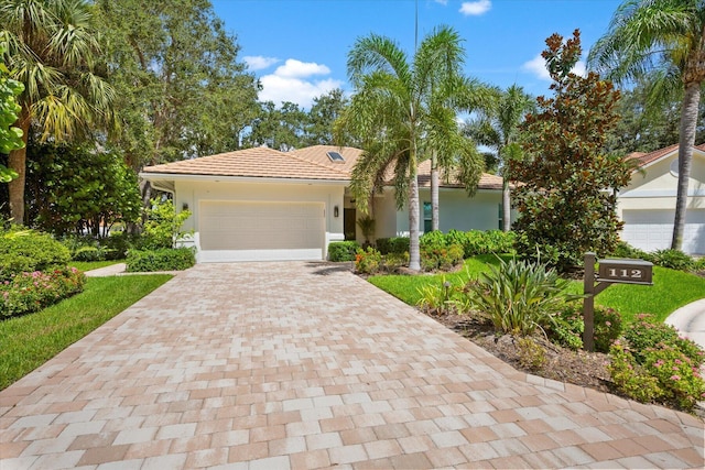 view of front facade with decorative driveway, a tile roof, an attached garage, and stucco siding