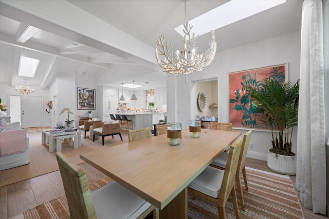 dining room with light wood-type flooring, a chandelier, and lofted ceiling with beams