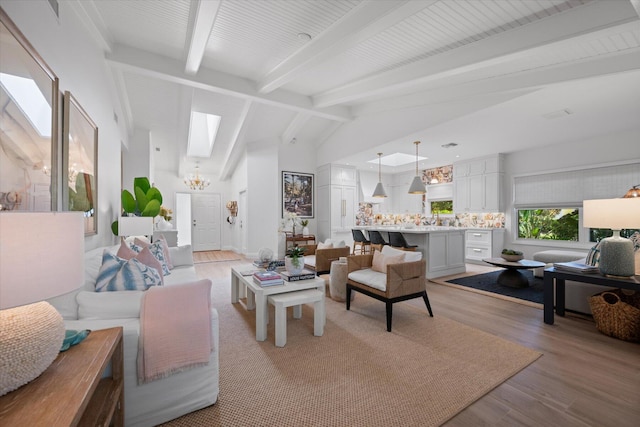 living room featuring an inviting chandelier, light wood-type flooring, and lofted ceiling with beams