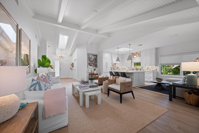 living area with a chandelier, light wood-style flooring, and lofted ceiling with beams