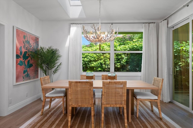 dining space featuring a skylight, wood-type flooring, and a chandelier