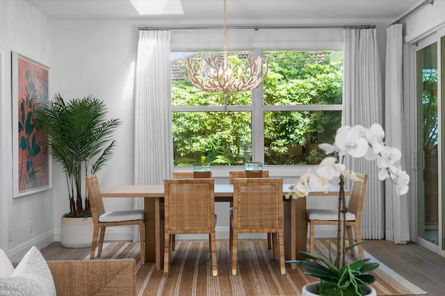 dining space with baseboards, a notable chandelier, and wood finished floors