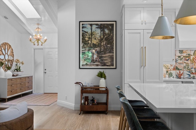 dining space featuring a skylight, an inviting chandelier, and light hardwood / wood-style flooring