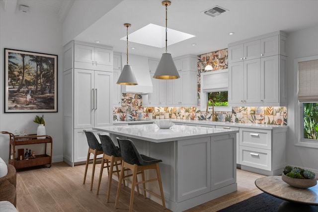 kitchen featuring light wood-type flooring, a kitchen island, tasteful backsplash, and a healthy amount of sunlight