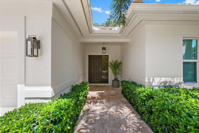 doorway to property with a garage and stucco siding