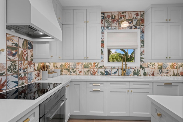 kitchen with custom exhaust hood, stainless steel oven, decorative backsplash, and white cabinetry