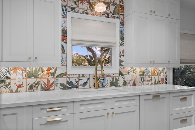 kitchen featuring sink, light stone countertops, decorative backsplash, and white cabinets