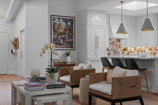 living room featuring baseboards, recessed lighting, a skylight, and light wood-style floors