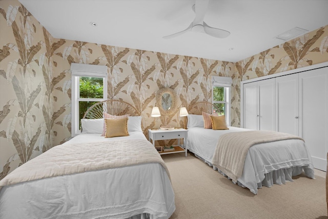 bedroom with a closet, ceiling fan, and light carpet