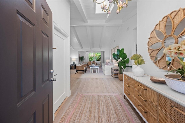 entryway with lofted ceiling with beams, light wood-style floors, and a chandelier