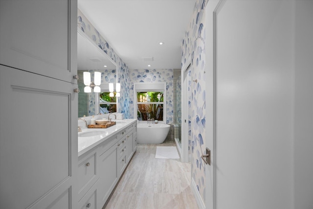 full bathroom featuring wallpapered walls, walk in shower, a freestanding bath, double vanity, and a sink