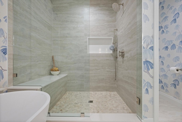 bathroom with a shower stall, a freestanding tub, and baseboards