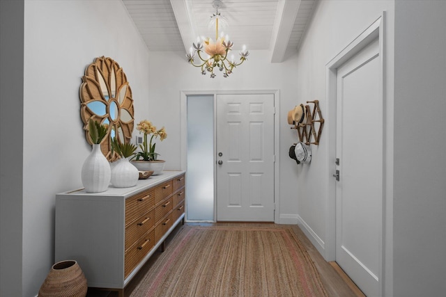 foyer entrance with an inviting chandelier, beamed ceiling, and hardwood / wood-style flooring