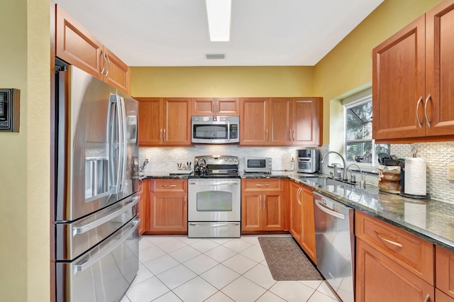 kitchen featuring tasteful backsplash, appliances with stainless steel finishes, sink, and dark stone countertops