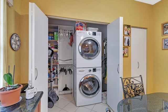 clothes washing area featuring light tile patterned flooring and stacked washer and clothes dryer