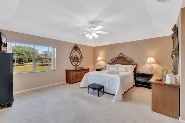 bedroom with ceiling fan, light colored carpet, and a tray ceiling