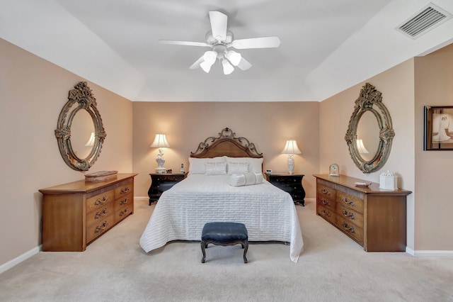 carpeted bedroom with a raised ceiling and ceiling fan