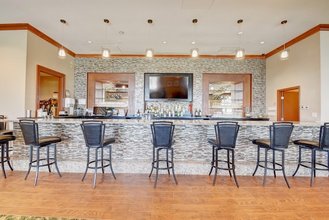 bar with crown molding, pendant lighting, and light wood-type flooring