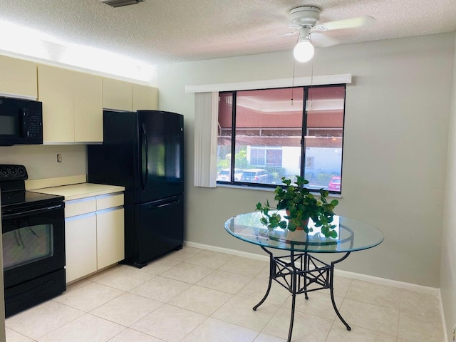 kitchen featuring cream cabinetry, black appliances, a textured ceiling, light countertops, and baseboards