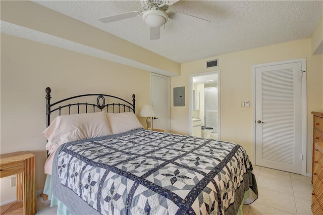 tiled bedroom with ceiling fan, a textured ceiling, and connected bathroom