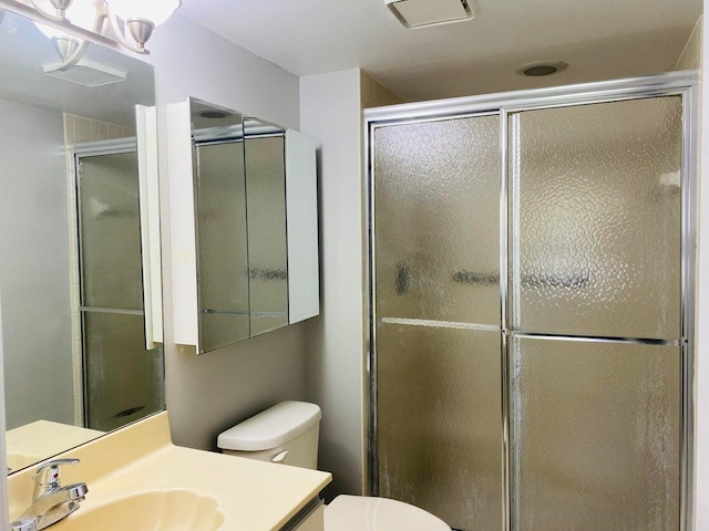 bathroom with vanity, a shower stall, and toilet