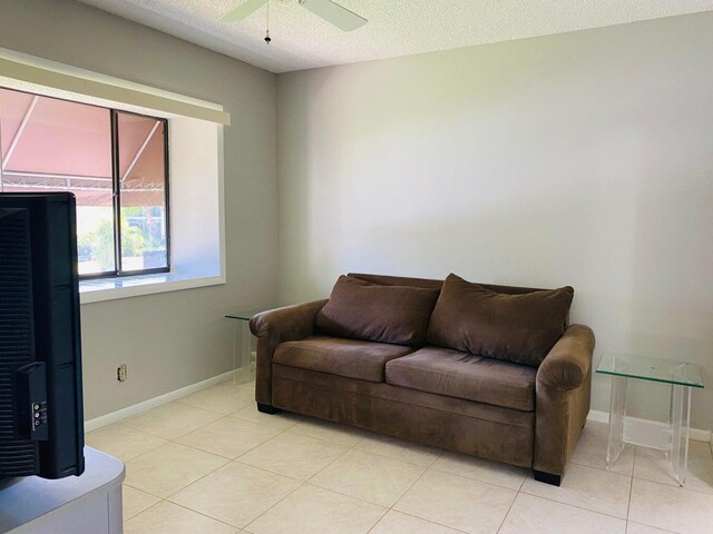 tiled living room with ceiling fan and a textured ceiling