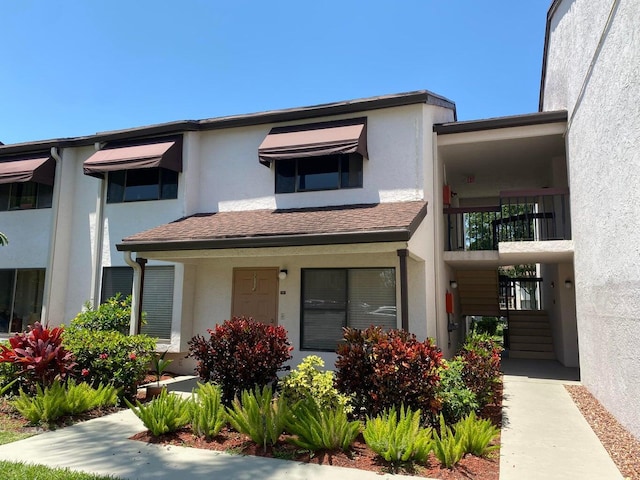 multi unit property with a shingled roof and stucco siding