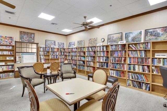 interior space with ceiling fan, light colored carpet, and crown molding