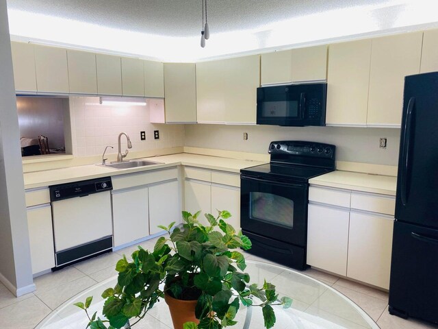 kitchen with a textured ceiling, black appliances, light tile patterned flooring, tasteful backsplash, and sink