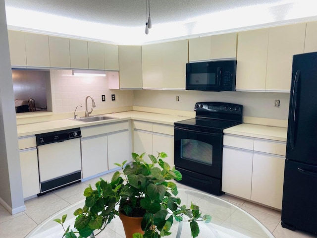 kitchen featuring black appliances, light countertops, light tile patterned flooring, a textured ceiling, and a sink