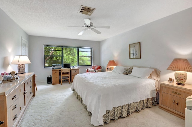 bedroom with a textured ceiling, ceiling fan, and light colored carpet