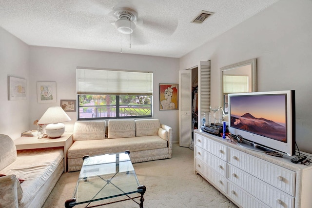 living room featuring light carpet, ceiling fan, and a textured ceiling