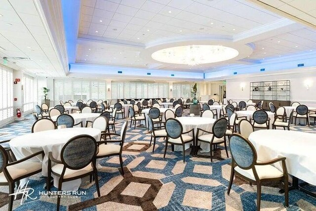 carpeted dining space with ornamental molding and a tray ceiling