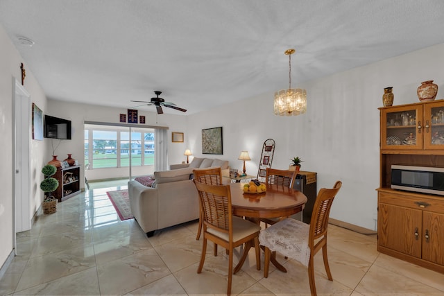 tiled dining room featuring ceiling fan with notable chandelier