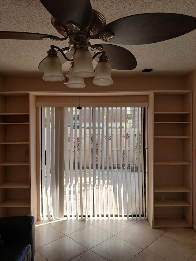 interior space featuring ceiling fan, light tile patterned flooring, and a textured ceiling