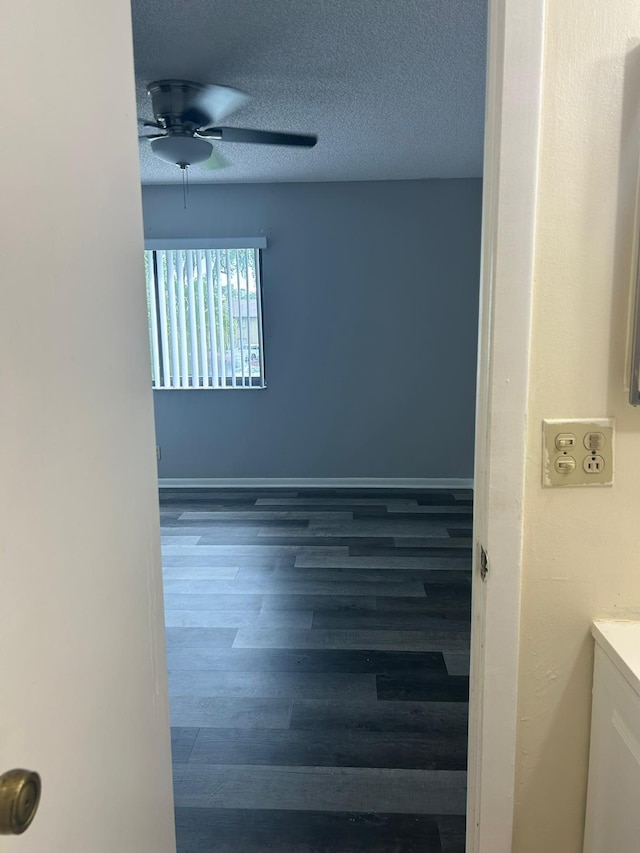 empty room with ceiling fan, wood-type flooring, and a textured ceiling