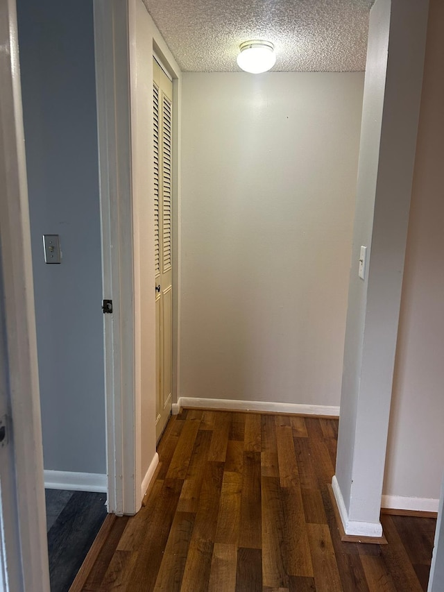 corridor featuring a textured ceiling and dark wood-type flooring