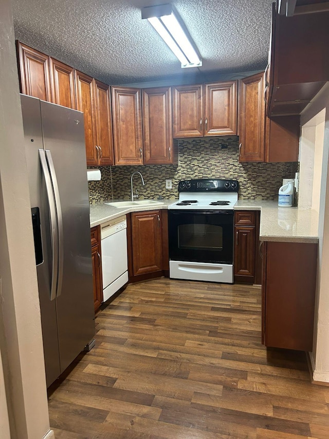 kitchen featuring dark hardwood / wood-style flooring, a textured ceiling, white appliances, sink, and tasteful backsplash