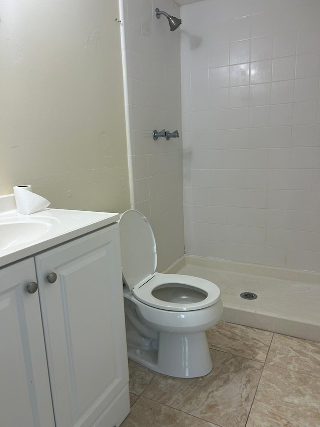 bathroom featuring tiled shower, toilet, vanity, and tile patterned flooring