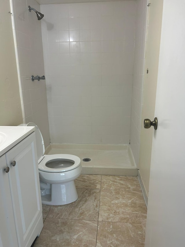 bathroom with tile patterned floors, a tile shower, vanity, and toilet